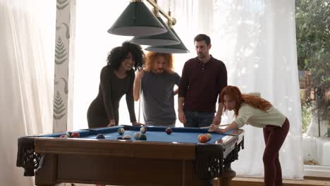 friends watching woman playing pool in game room