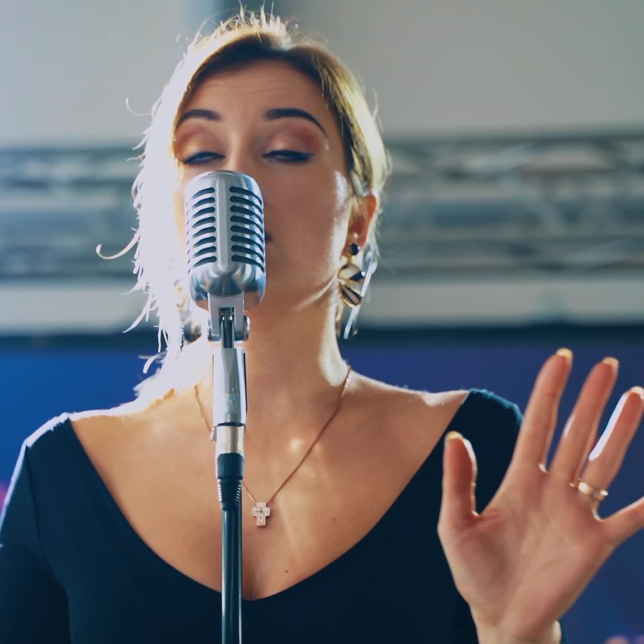 Portrait of a beautiful young singer. Blonde woman standing on the stage and singing into the microphone. Slow motion.