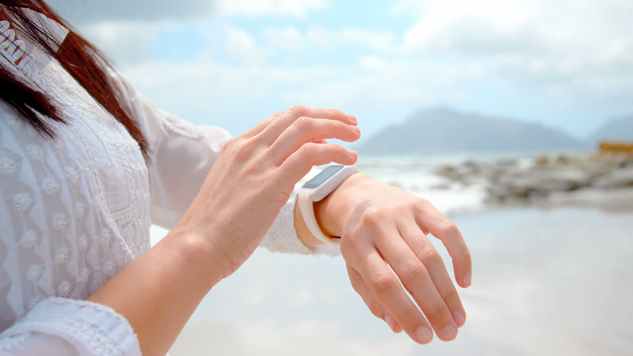 Mezza figura di donna che usa lo smartwatch in spiaggia 4K.