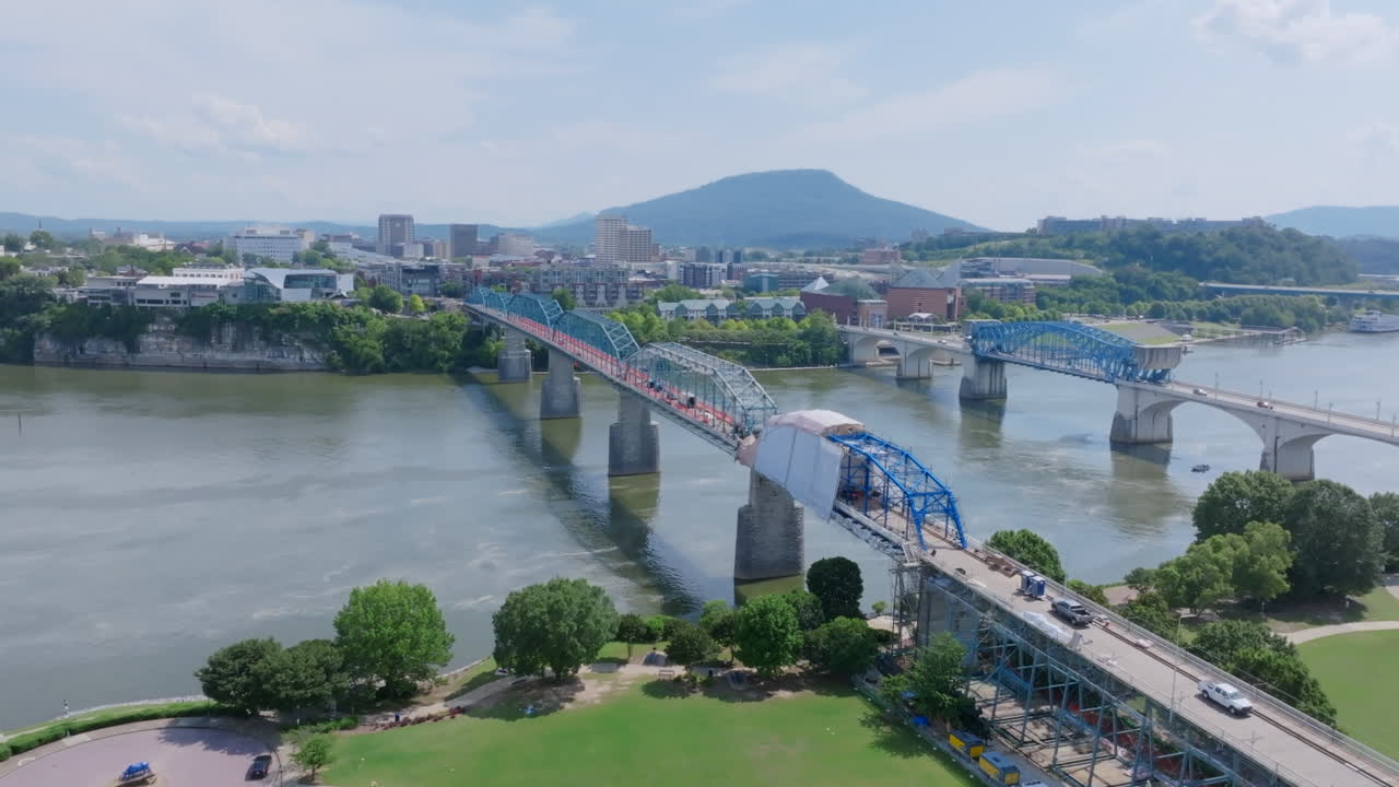 An aerial view of downtown Chattanooga, TN, showcases the Walnut Street Bridge under renovation, with the Tennessee River and Lookout Mountain visible in the background