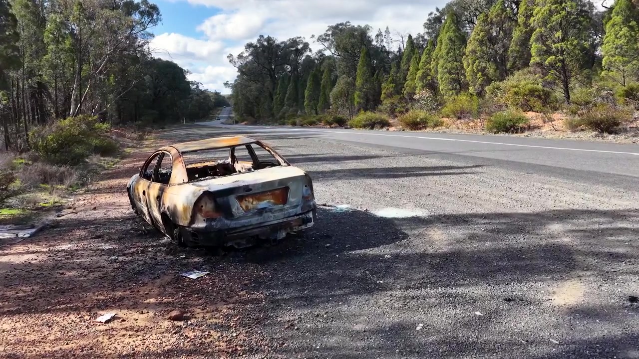 En udbrændt sedan står forladt på en afsidesliggende motorvejsrabat i Goonoo Forest, Australien.