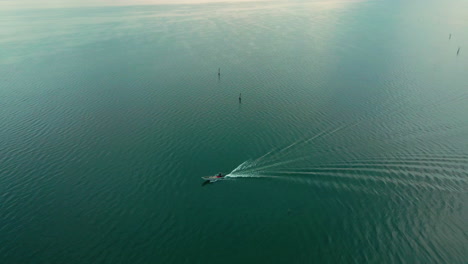 Fischer-Auf-Einem-Kleinen-Motorboot,-Das-Am-Frühen-Morgen-In-Italien-In-Den-Ruhigen-Gewässern-Des-Trasimenischen-Sees-Fährt