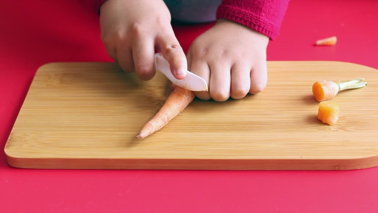 Close-up of Child's Hands Peeling a Carrot on a Cutting Board