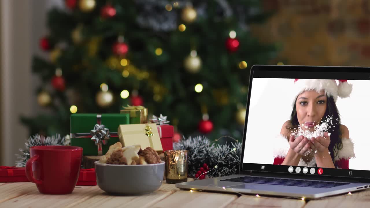 feliz mujer caucásica en disfraz de santa en videollamada en computadora portátil, con decoraciones de navidad y árbol