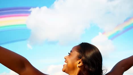 woman smiling and looking up at a rainbow in the sky