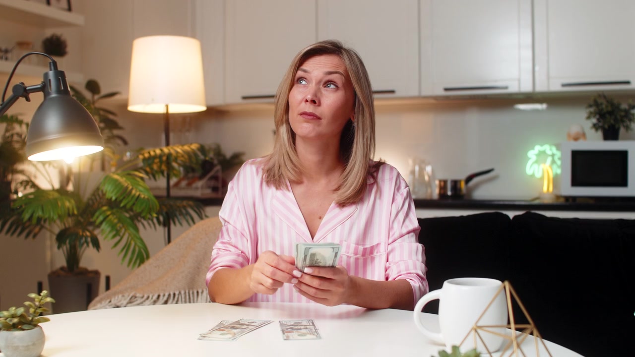 Mujer adulta contando dólares en efectivo, organizando pilas de presupuesto, gastos, ahorros, planes financieros familiares, plan nocturno.