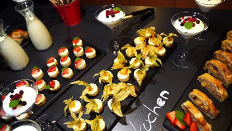 delicious dessert buffet with small appetizers on a black plate and fear mugs at an event