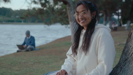 smiling asian girl posing on camera in the park