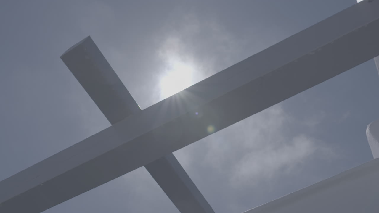 푸른 하늘 앞에 나무 천장 프레임의 낮은 각도 촬영 태양이 불꽃 로그를 만드는