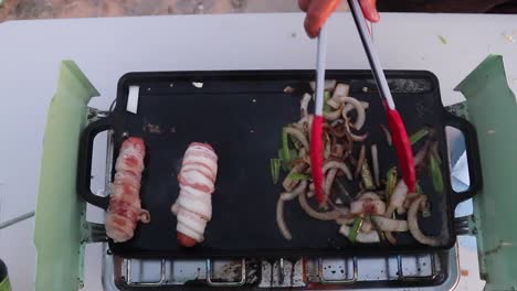cocinar tocino en una sartén con cebolla al lado