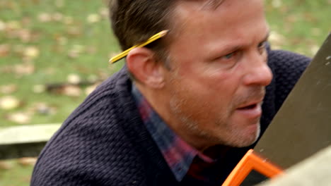 close up of man fixing outdoor fence with saw