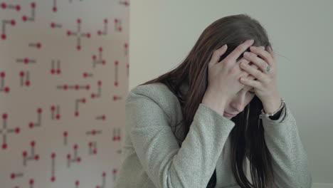 Young-stressed-woman-holding-head-while-sitting-in-office,-job-causing-headache