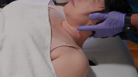 woman lying down with eyes closed receiving a gentle neck massage on one side of her head