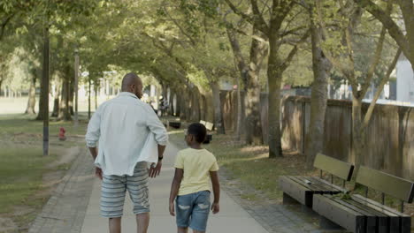 Vater-Und-Sohn-Spazieren-An-Einem-Warmen-Sommertag-Die-Straße-Im-Park-Entlang.