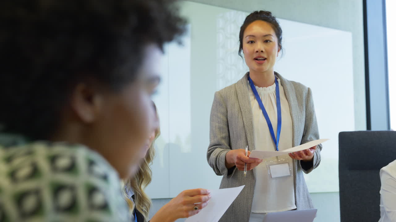 Donna d'affari guida un team aziendale multiculturale che si riunisce e collabora attorno a un tavolo in ufficio.
