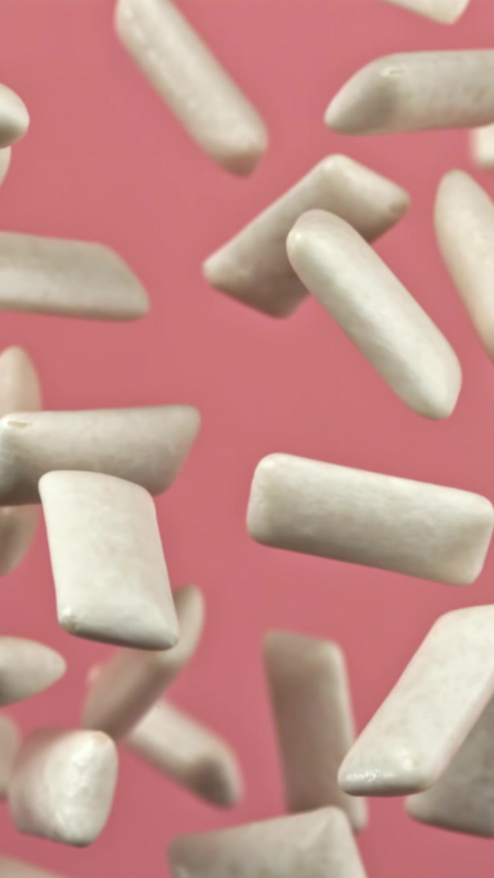 Pezzi di gomma da masticare bianca fresca che cadono al rallentatore su sfondo rosa