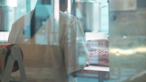 Butchers-at-work,-seen-through-window,-back-view