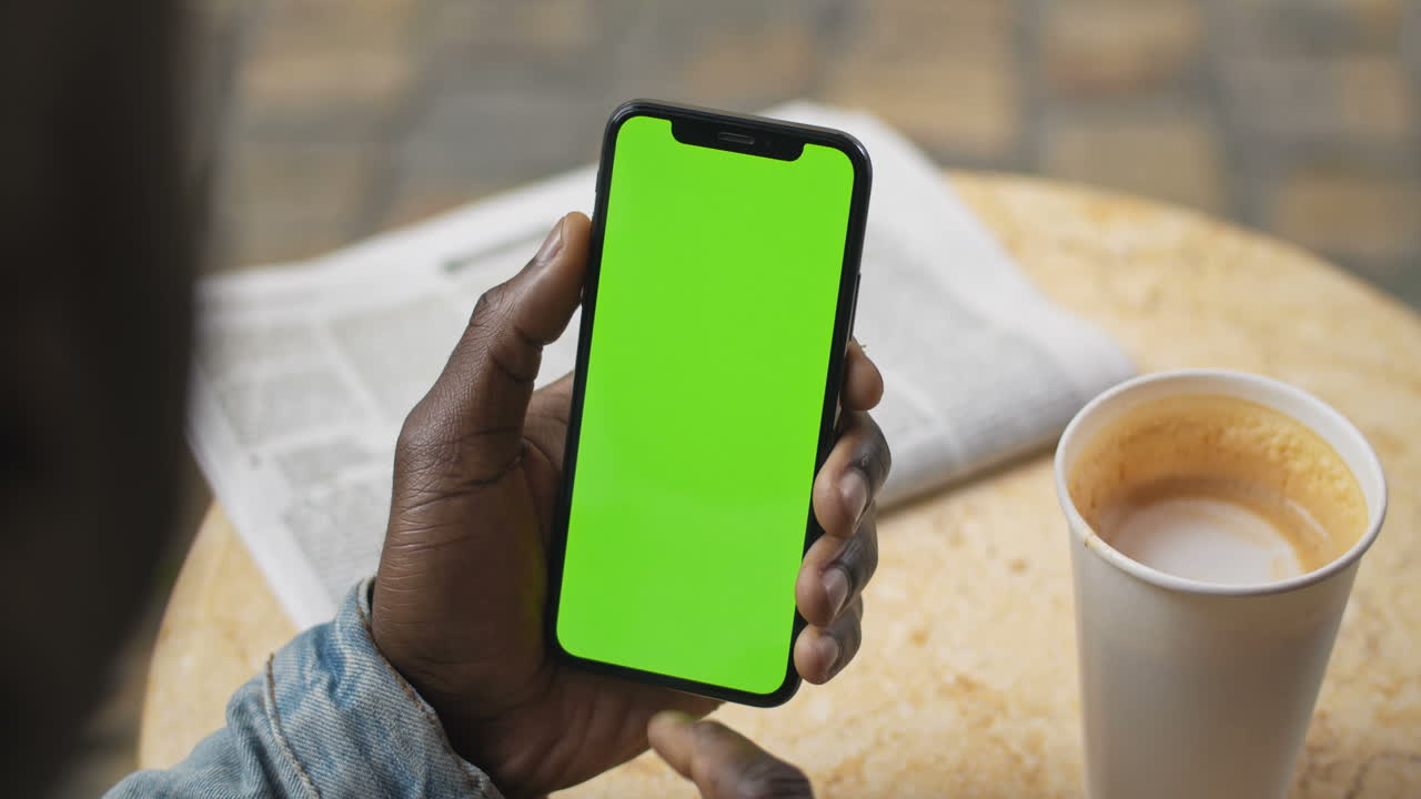 Smartphone med grøn skærm på café