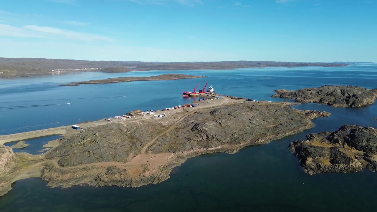 Ilmadrone suorittaa eteenpäin oikealle työntävää liikettä kallistuen kohti syvävesilaituria ja konttien varastointialuetta Iqaluitin satamassa.