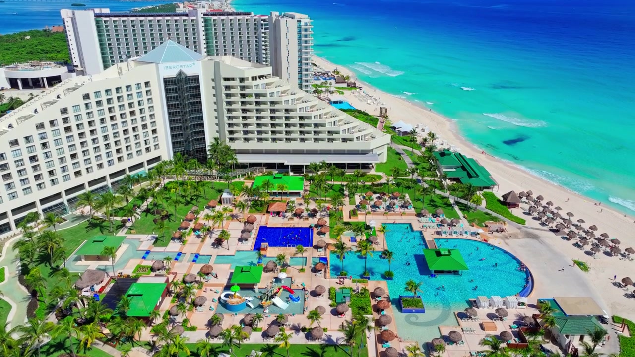 Meksika, Quintana Roo'daki Cancun Otel Bölgesi'nin turkuaz plajının yanında, özenle tasarlanmış havuzlara sahip büyük bir piramit tatil köyünün havadan görünümü.