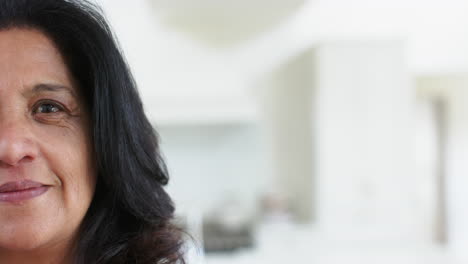 Half-face-of-happy-caucasian-senior-woman-standing-and-smiling-in-sunny-room-at-home,-slow-motion