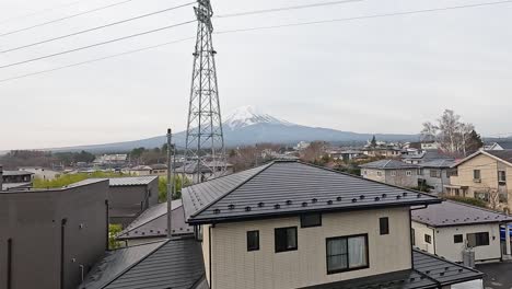 a serene view of mount fuji from kawaguchiko, japan, captured over rooftops with overcast lighting and static camera