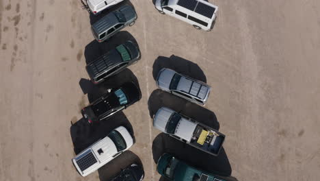 vista aérea de arriba hacia abajo de una fila de autos y camiones en el desierto