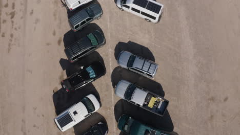 aerial top-down view of a row of cars and trucks in the desert