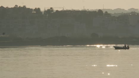 Barco-De-Pesca-Cruzando-El-Río-En-Una-Mañana-Soleada-Reflejos-De-La-Luz-Del-Sol,-Portimão---Algarve