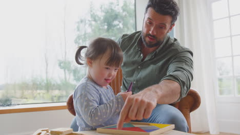 Padre-Con-Hija-Con-Síndrome-De-Down-Jugando-Con-Formas-De-Madera-En-Casa-Juntos