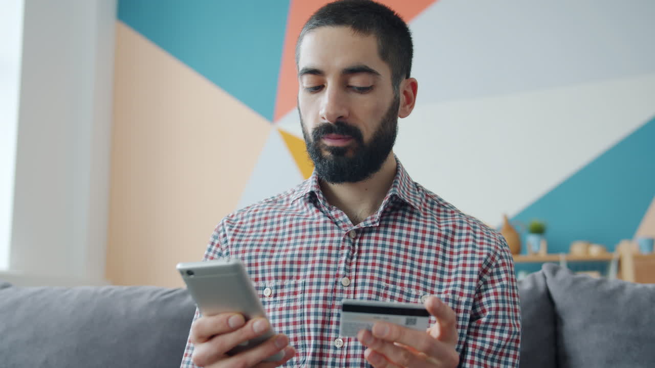 Uomo che effettua un pagamento mobile sul divano