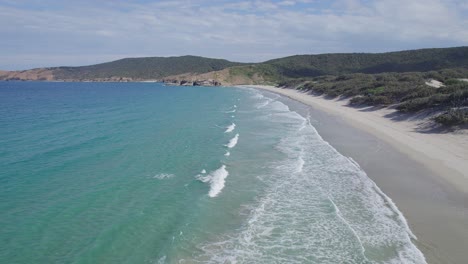 sea waves splashing on white sand at long beach in great keppel island, australia