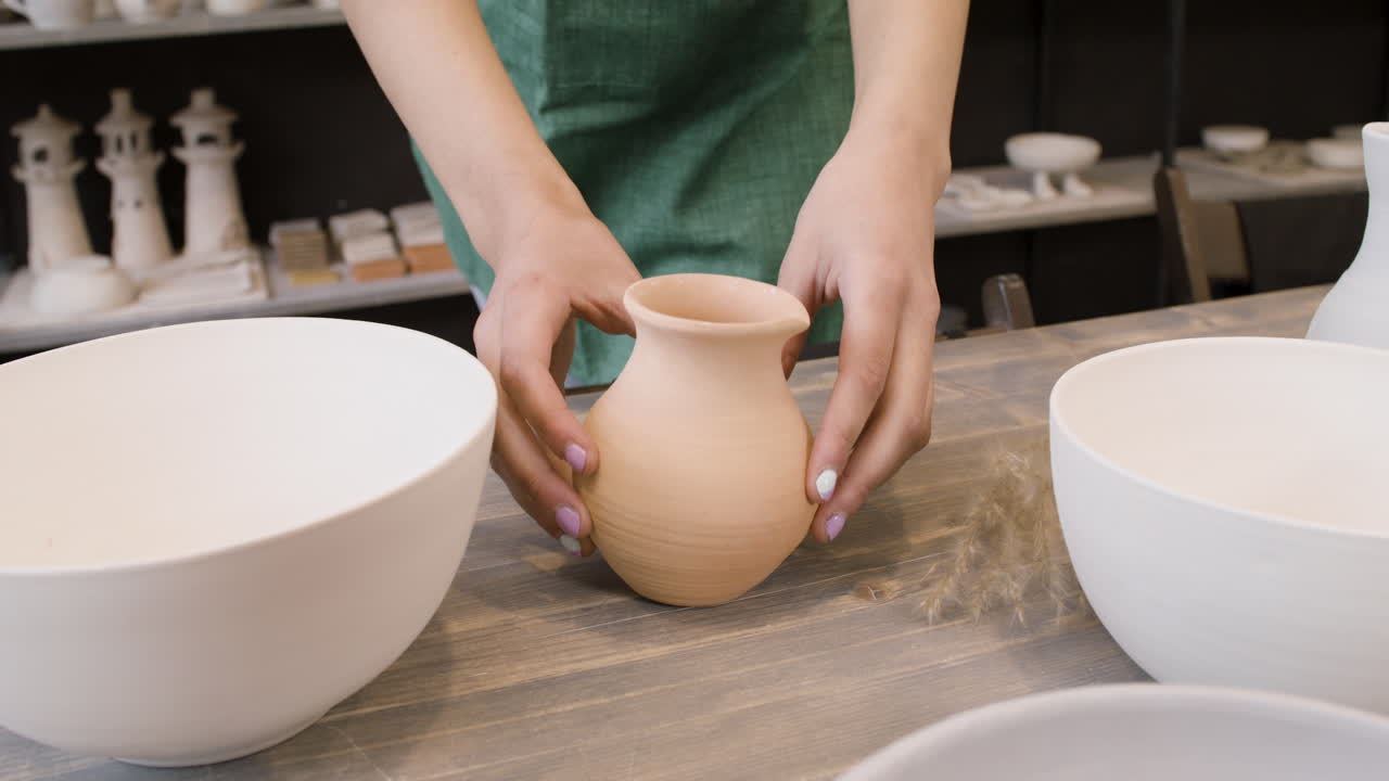 도자기 가게의 탁자 위에 도자기 주전자를 놓고 알아볼 수 없는 여자를 가까이서