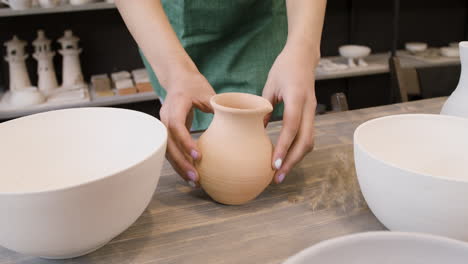 gros plan d'une femme méconnaissable mettant une cruche en céramique sur une table dans le magasin de poterie