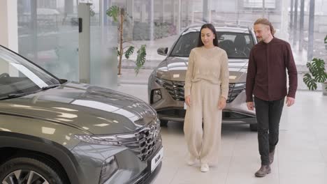 beautiful young couple at car showroom choosing a new car to buy.