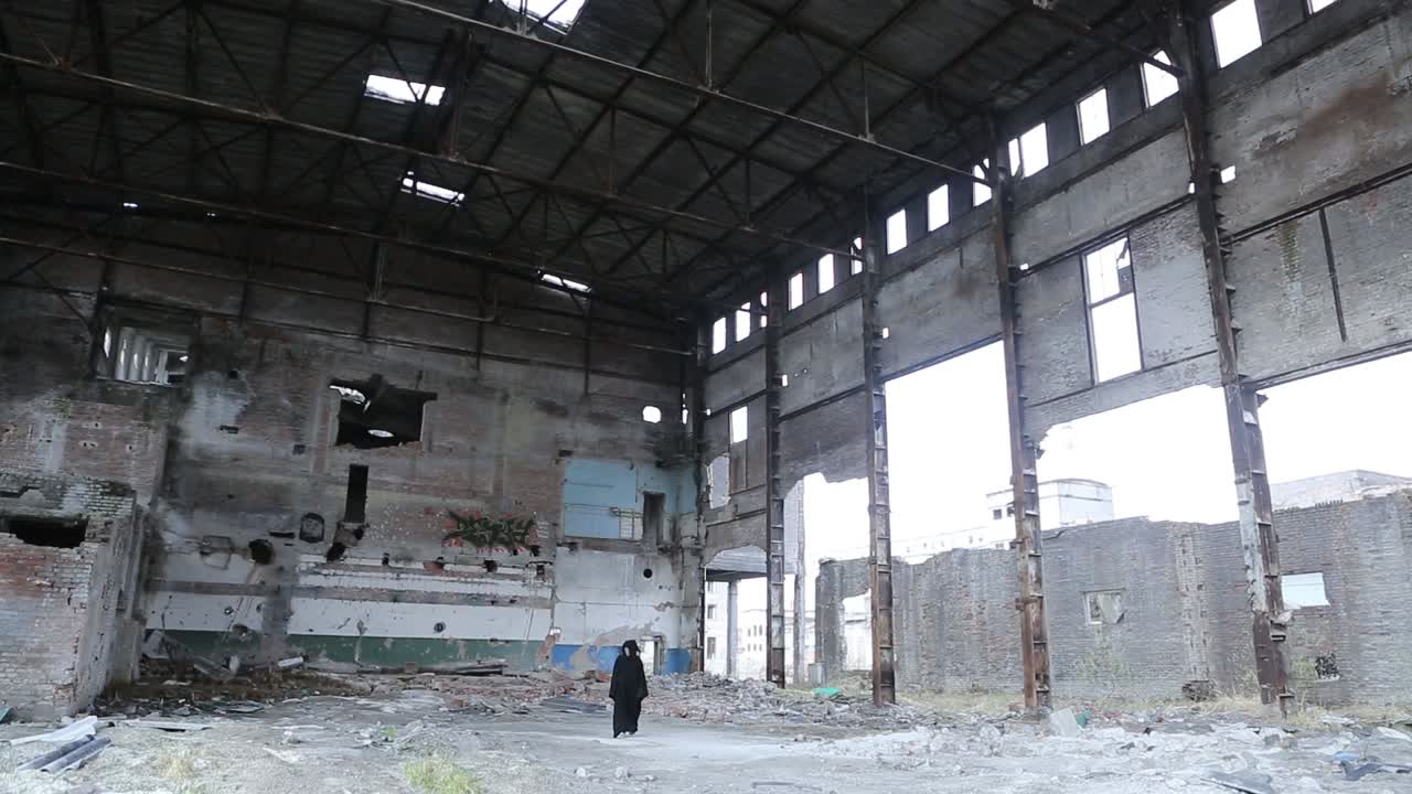 Mysterious person walking in an old destroyed factory