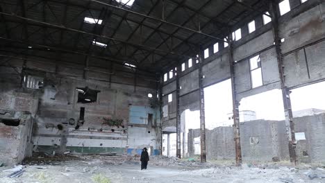 mysterious person walking in an old destroyed factory