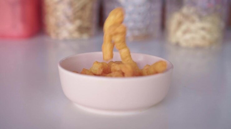 crispy fried snacks falling into a white ceramic bowl. Snack time, crunchy food and casual eating concept footage.