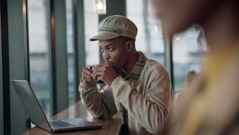 Hombre-Negro-Escribiendo-En-Una-Computadora-Portátil-En-La-Cafetería