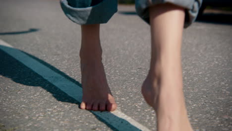 barefoot person walking on a road