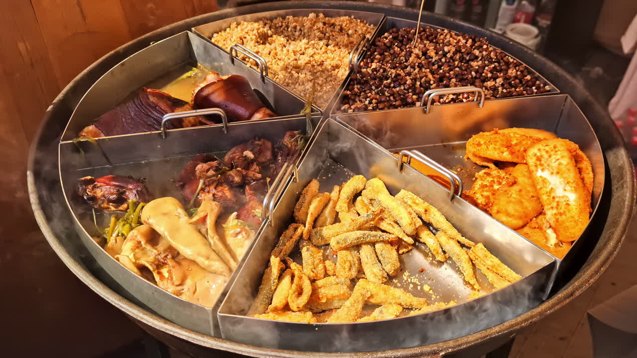 Steaming assorted street food in large round tray with fried and stewed mix