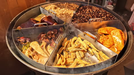 steaming assorted street food in large round tray with fried and stewed mix