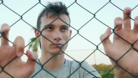 retrato de un adolescente triste mirando a través de la cuadrícula