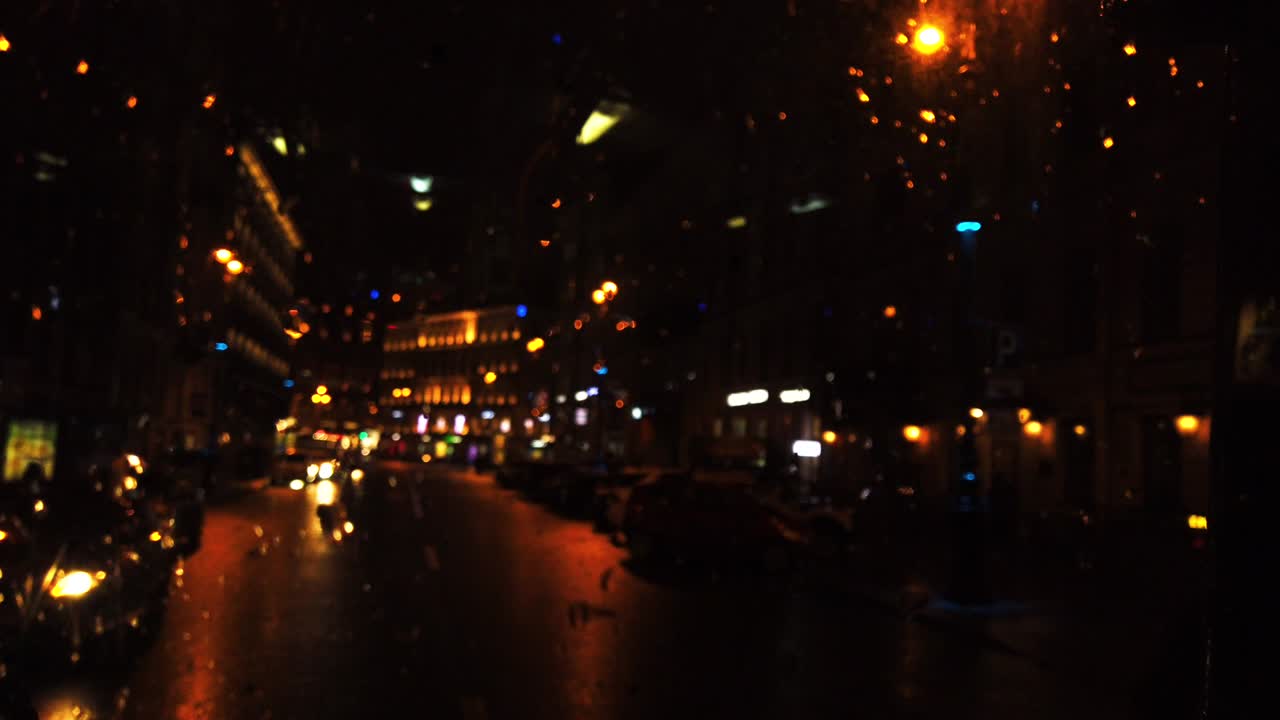 비가 내리는 동안 밤의 도시 거리에서 초점을 맞추지 않은 불빛
