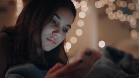 beautiful teenage girl lying on bed texting using smartphone browsing social media online chat enjoying evening relaxing at home