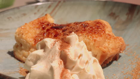 close up shot of torrija, a spanish dessert made of french toast with cream on a brown plate