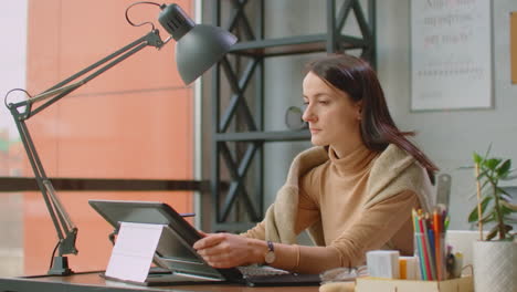 young woman sitting at her desk she's drawing writing and using pen with digital tablet computer. hands with pen