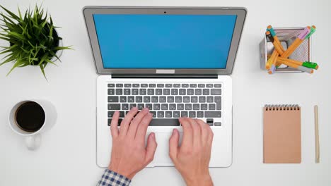a man's hands typing on the laptop