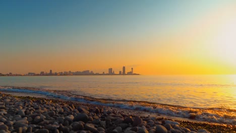 city of batumi in georgia is visible in distance in sea at sunset.