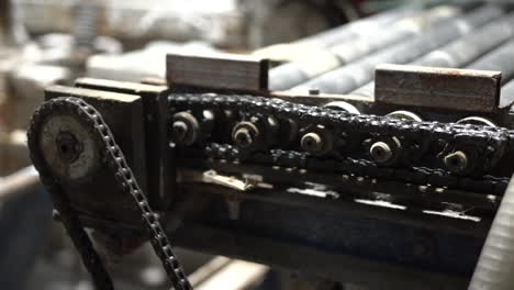 primer plano de engranajes giratorios y cadenas en el rodillo transportador de la máquina industrial